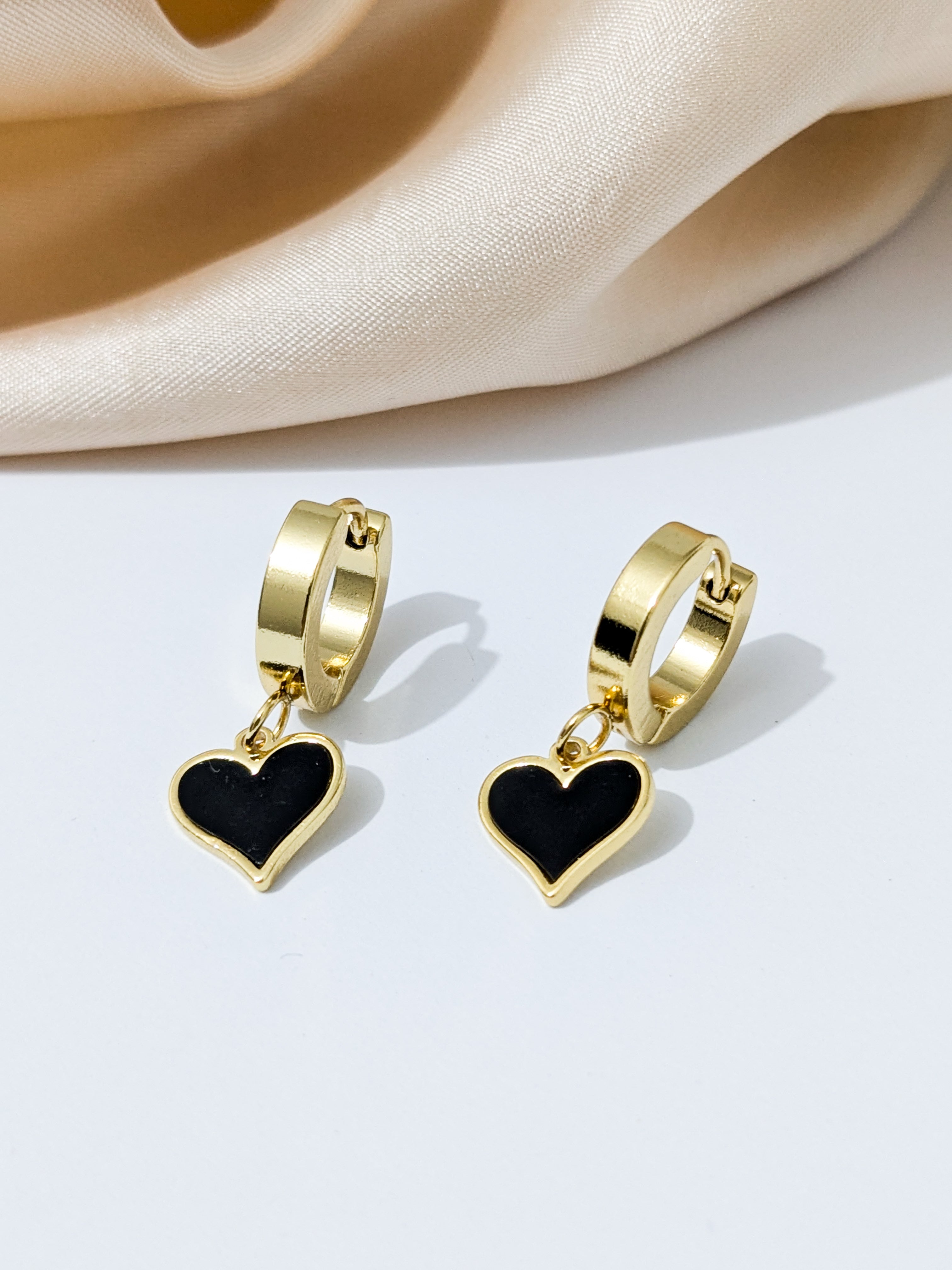 Gold hoop earrings with black heart-shaped dangles