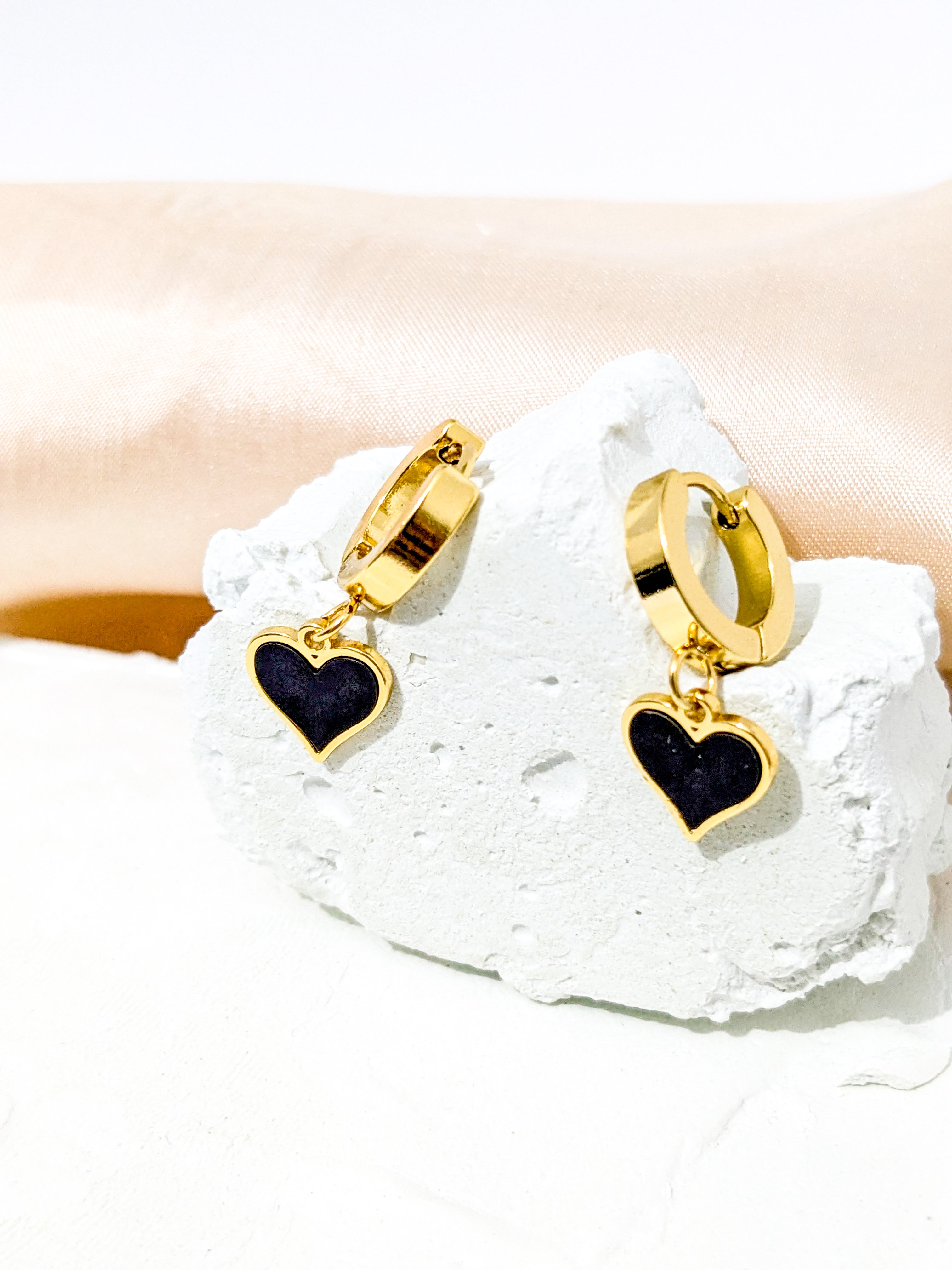 Gold hoop earrings with black heart-shaped dangles